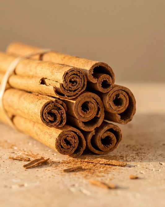Bâtons de cannelle et une pincée de cannelle moulue sur travertin : la senteur épicée, douce et chaude de l’huile essentielle pure de cannelle Delune