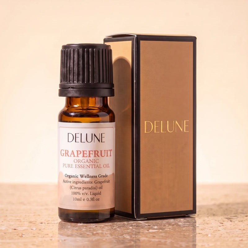 Huile essentielle biologique de pamplemousse Delune, flacon de 10 ml en verre ambré avec son coffret-cadeau Delune à dorure sur pierre de travertin chaude