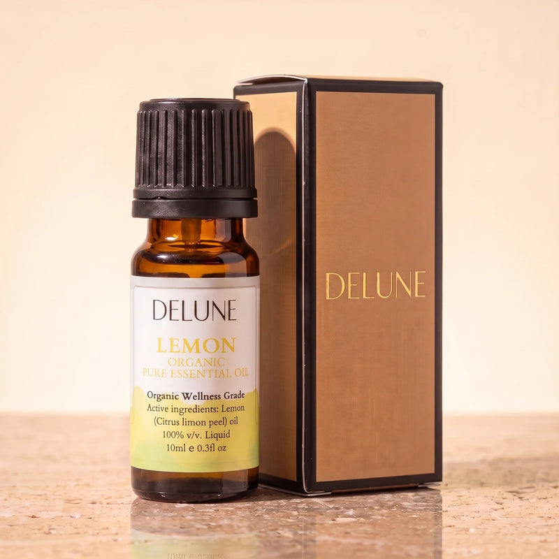 Huile essentielle biologique de citron Delune, flacon de 10 ml en verre ambré avec son coffret-cadeau Delune à dorure sur pierre de travertin chaude