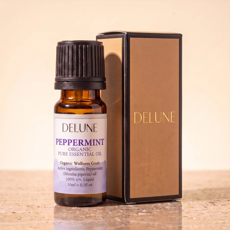 Huile essentielle biologique de menthe poivrée Delune, flacon de 10 ml en verre ambré avec son coffret-cadeau Delune à dorure sur pierre de travertin chaude