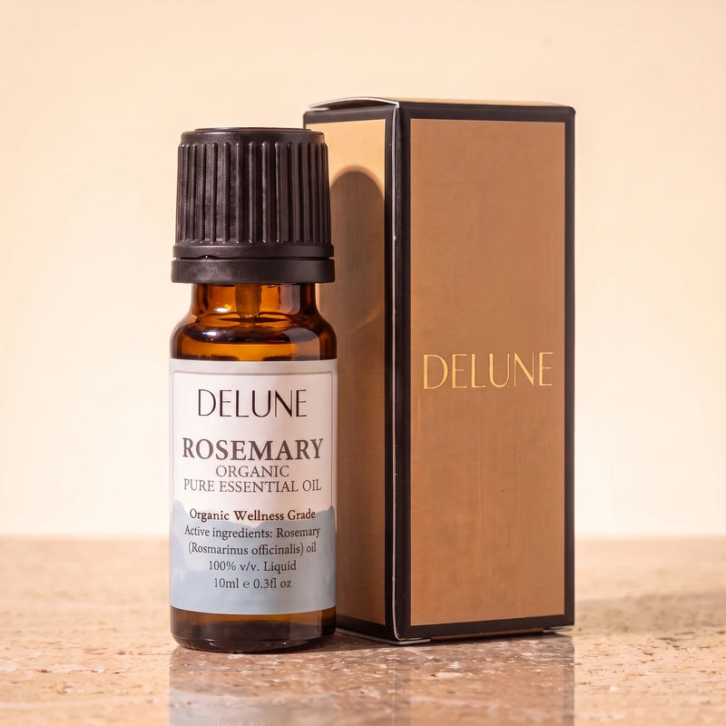 Huile essentielle biologique de romarin Delune, flacon de 10 ml en verre ambré avec son coffret-cadeau Delune à dorure sur pierre de travertin chaude
