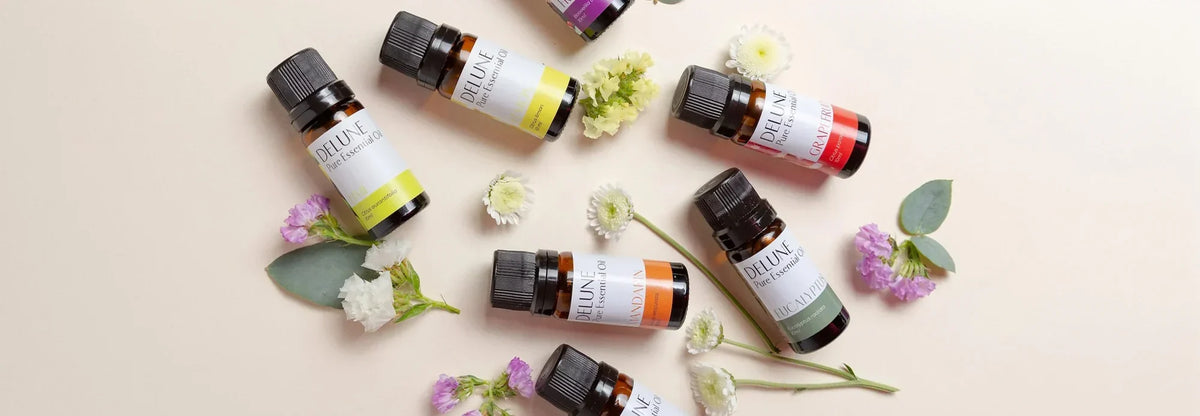 Flacons d’huiles essentielles Delune disposés avec des fleurs fraîches et de l’eucalyptus