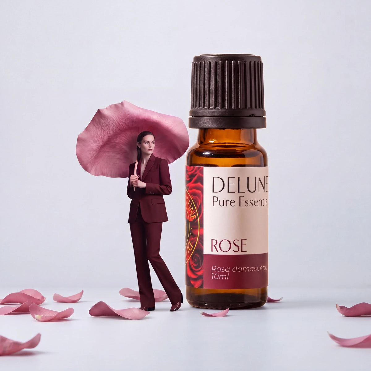Nature : une femme sous un pétale de rose géant, près d’un flacon géant d’huile essentielle pure de rose Delune