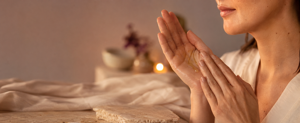 Adult woman warming facial oil between her palms during an evening skincare ritual